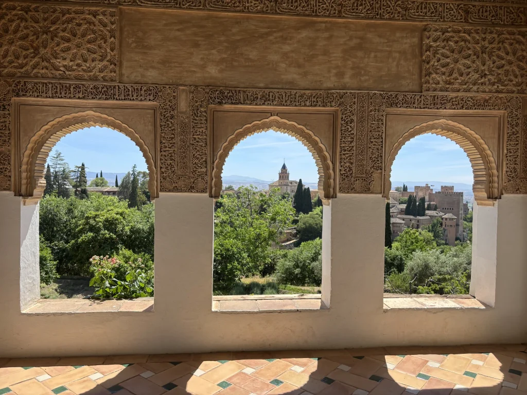 Vista su Granada dalle arcate nasridi dell’Alhambra con giardini e torri sullo sfondo