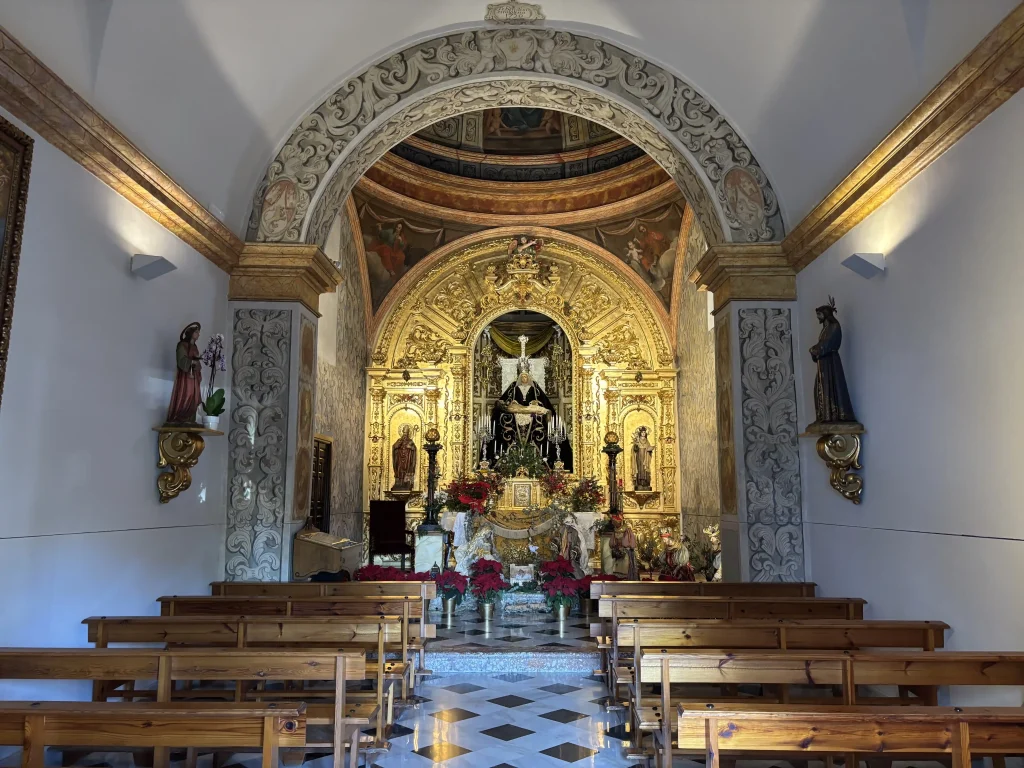 Interno della Ermita della Nuestra Señora de las Angustias di Nerja con altare barocco dorato e statue sacre