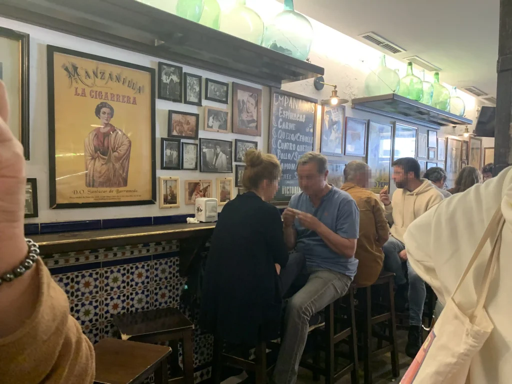 Mangiare a Málaga, Interno della taberna La Tranca a Málaga con persone sedute al bancone e decorazioni tradizionali