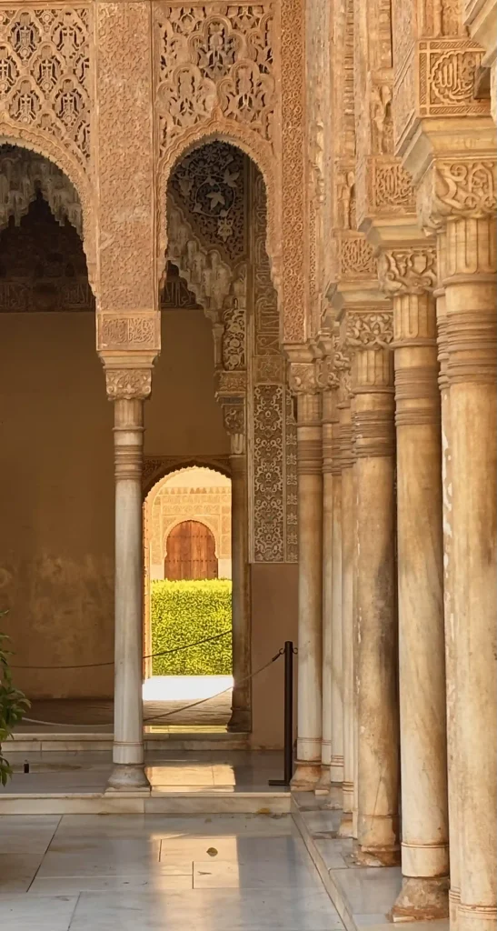 Colonnato dei Palazzi Nasridi dell’Alhambra con archi decorati e giardini sullo sfondo