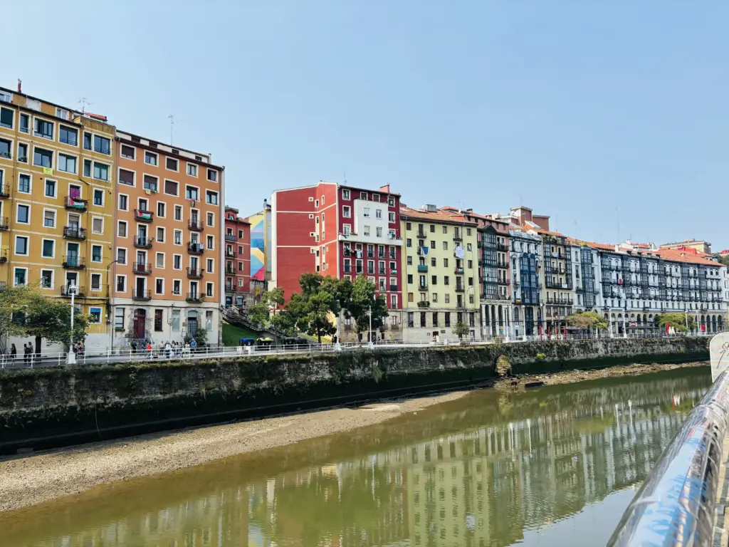Case colorate di Bilbao La Vieja lungo la Ría del Nervión con murale urbano sullo sfondo