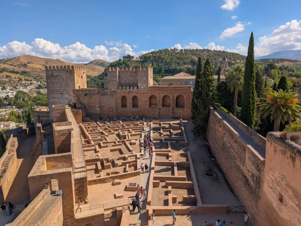 Alcazaba dell’Alhambra a Granada con torri e resti archeologici sotto un cielo azzurro