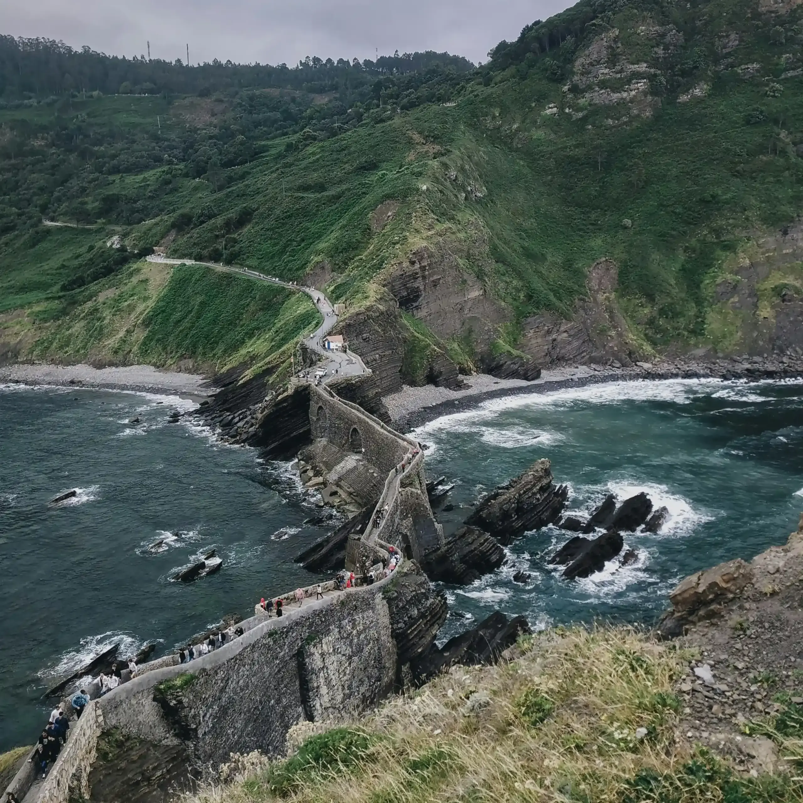 Vista dall’alto del ponte di San Juan de Gaztelugatxe con scogliere, oceano e sentiero costiero nei Paesi Baschi