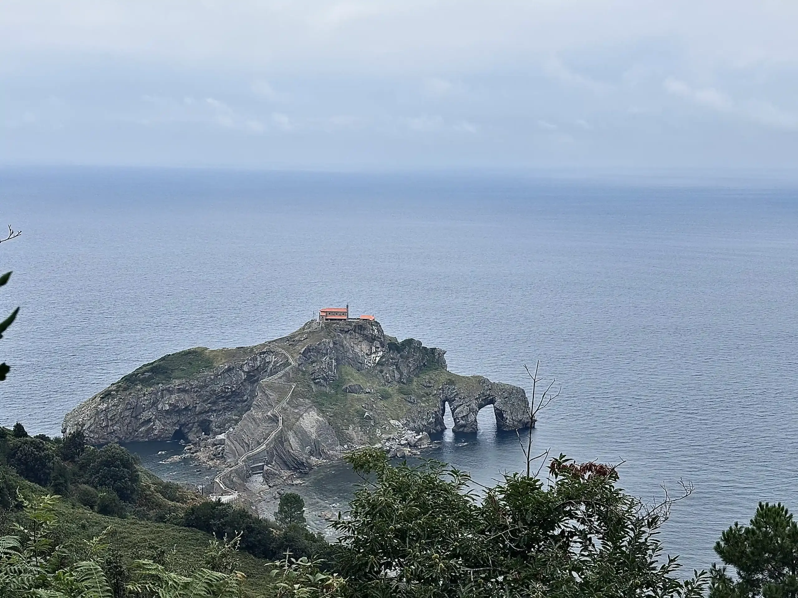 Vista panoramica di San Juan de Gaztelugatxe dall’alto con eremo, scalinata e oceano Atlantico