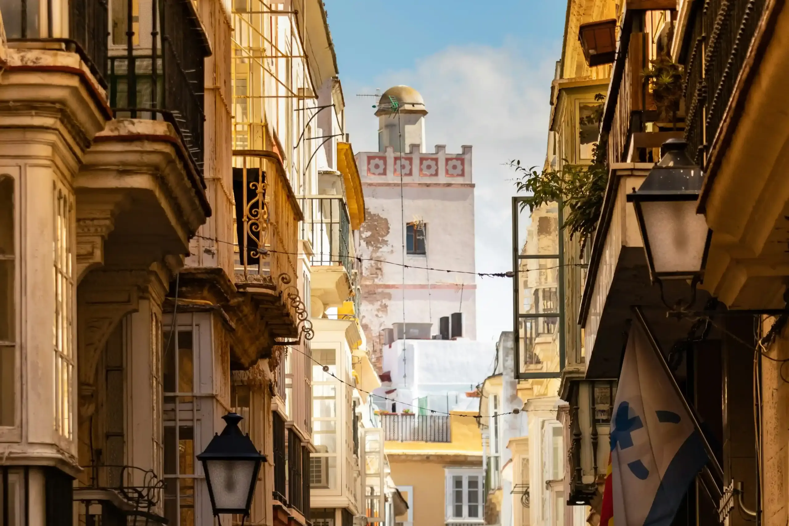 Vicolo stretto nel centro storico di Cádiz con balconi andalusi e Torre Tavira sullo sfondo