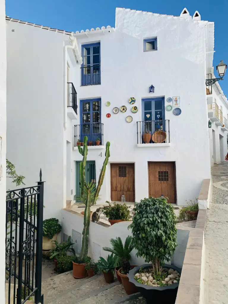 Casa bianca nel centro storico di Frigiliana con balconi, piatti decorativi e piante in vaso