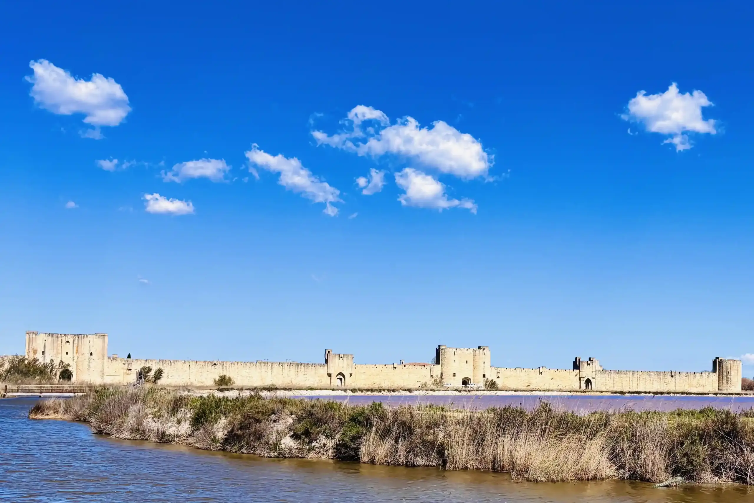 Fortificazioni di Aigues-Mortes viste dalle saline in Camargue sotto un cielo azzurro