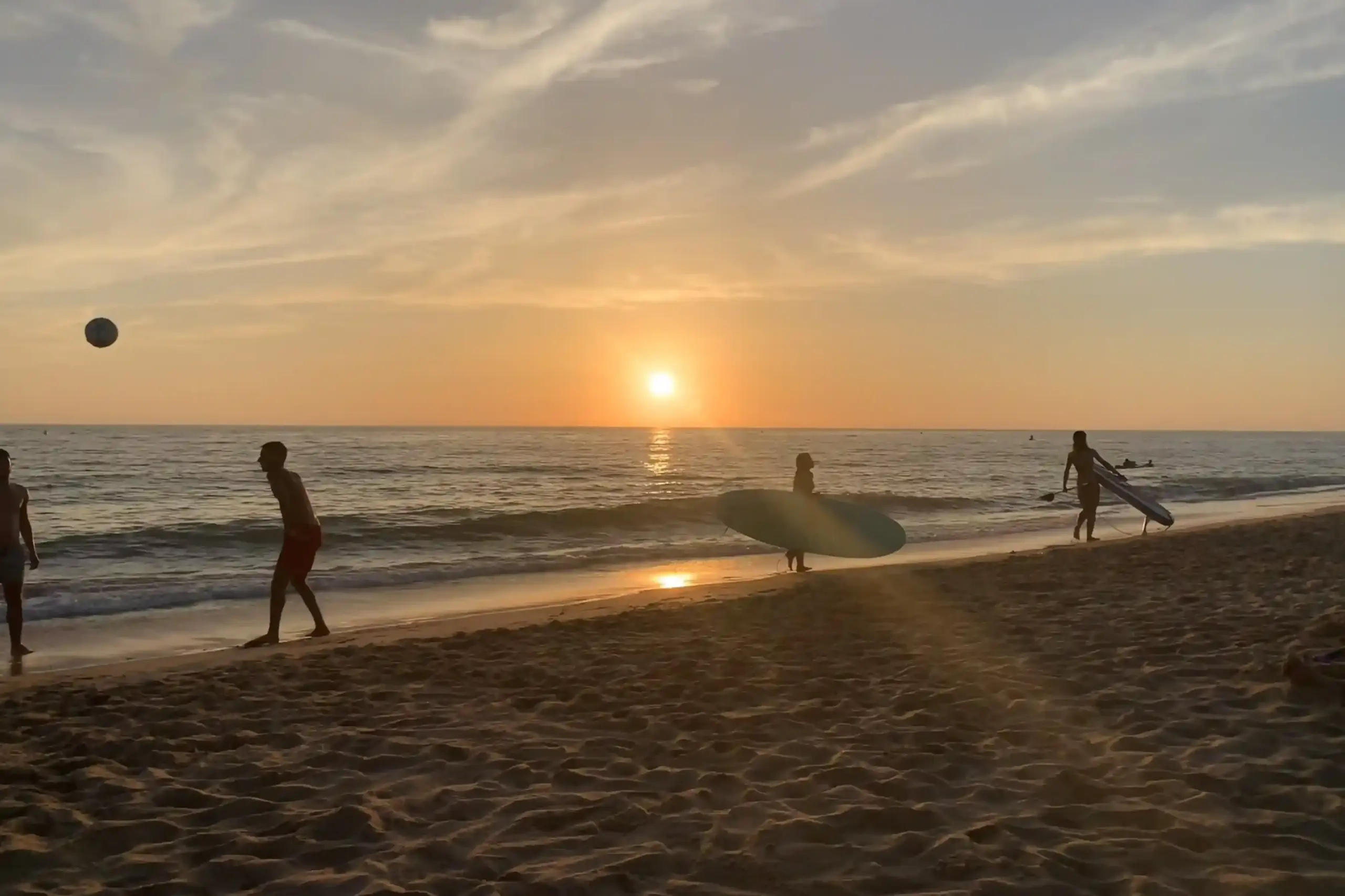 Spiaggia di El Palmar, tra Conil e Vejer de la Frontera, al tramonto con surfisti e persone sulla riva in controluce