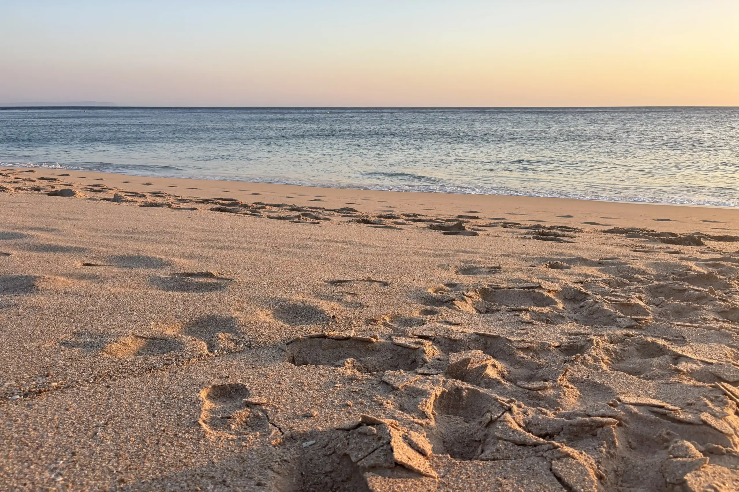 Playa del Cañuelo con sabbia dorata, impronte sulla riva e mare calmo al mattino