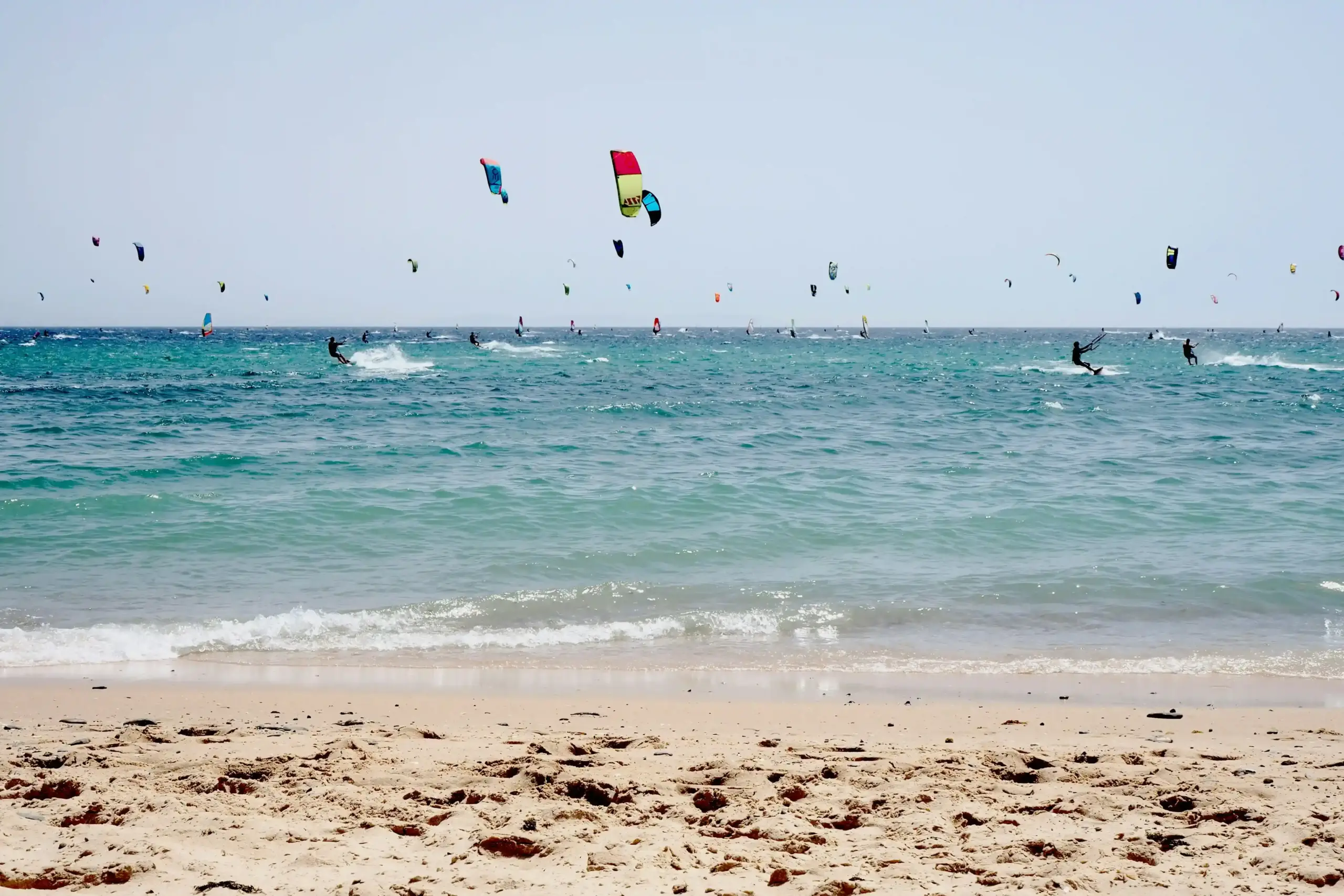 Kitesurfisti a Playa de Valdevaqueros con aquiloni colorati e mare turchese a Tarifa nella Costa de la Luz