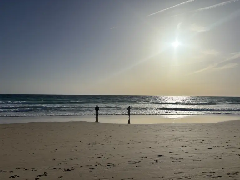 Spiaggia di Zahara de los Atunes con due persone sulla riva e luce del sole sul mare