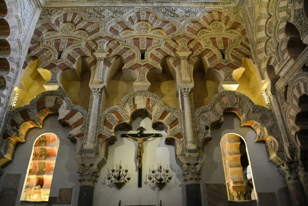 Dettaglio degli archi decorati della Mezquita di Córdoba con motivi islamici e crocifisso cristiano