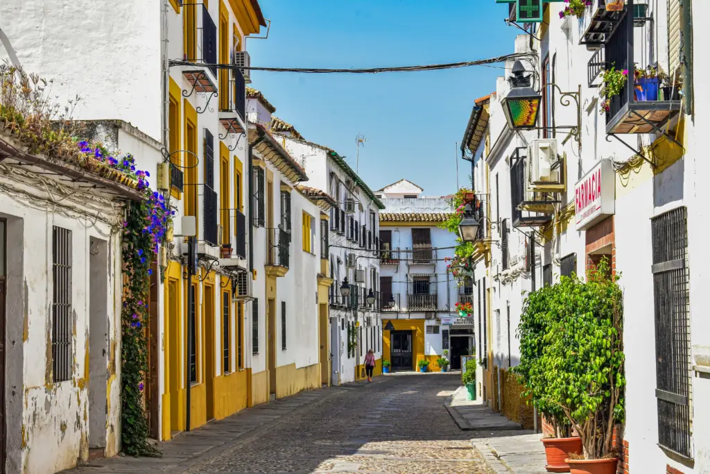 Vicolo del centro storico di Córdoba con case bianche, balconi fioriti e strada acciottolata