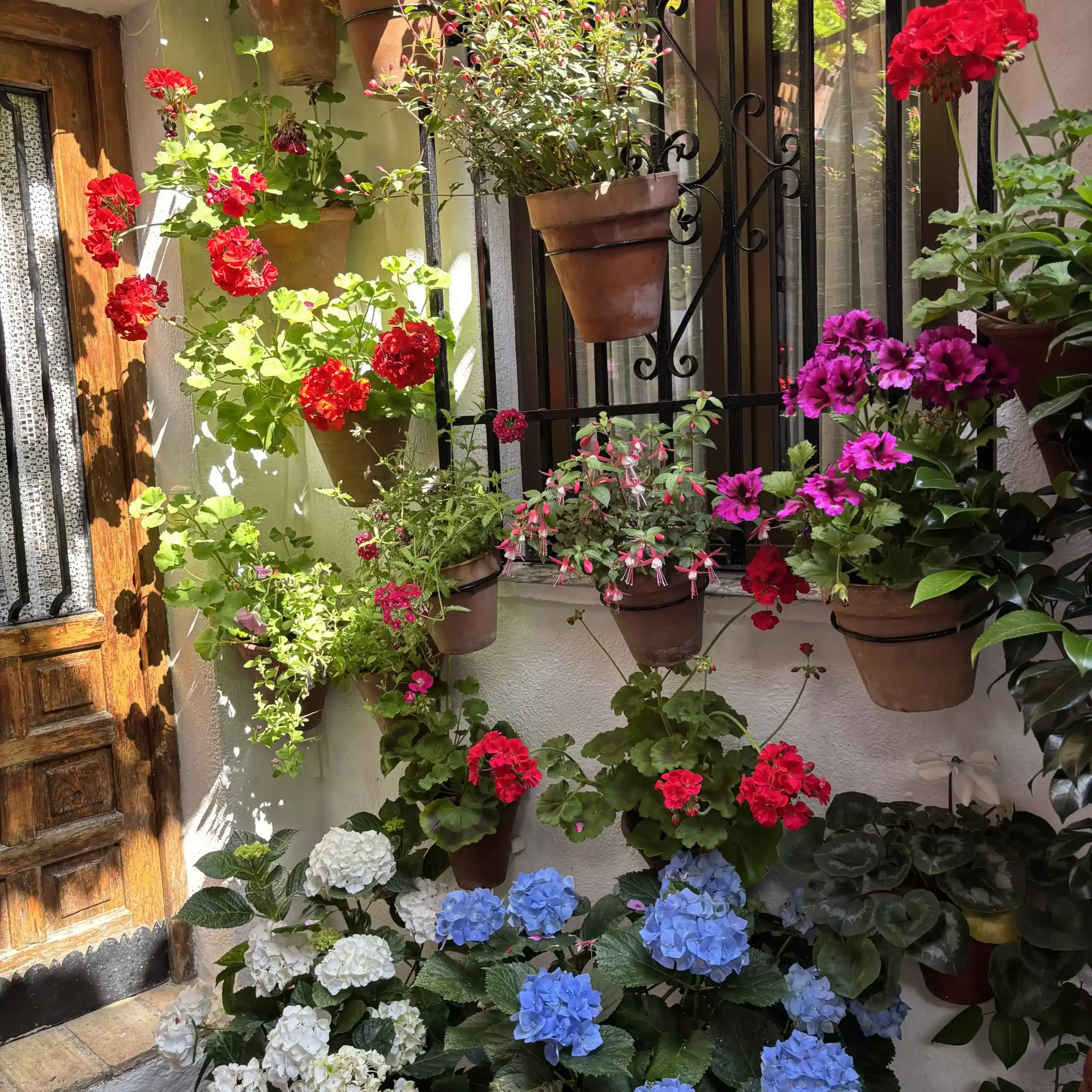 Patio di Córdoba con vasi di fiori su parete bianca e scala esterna durante il Festival de los Patios di Cordoba