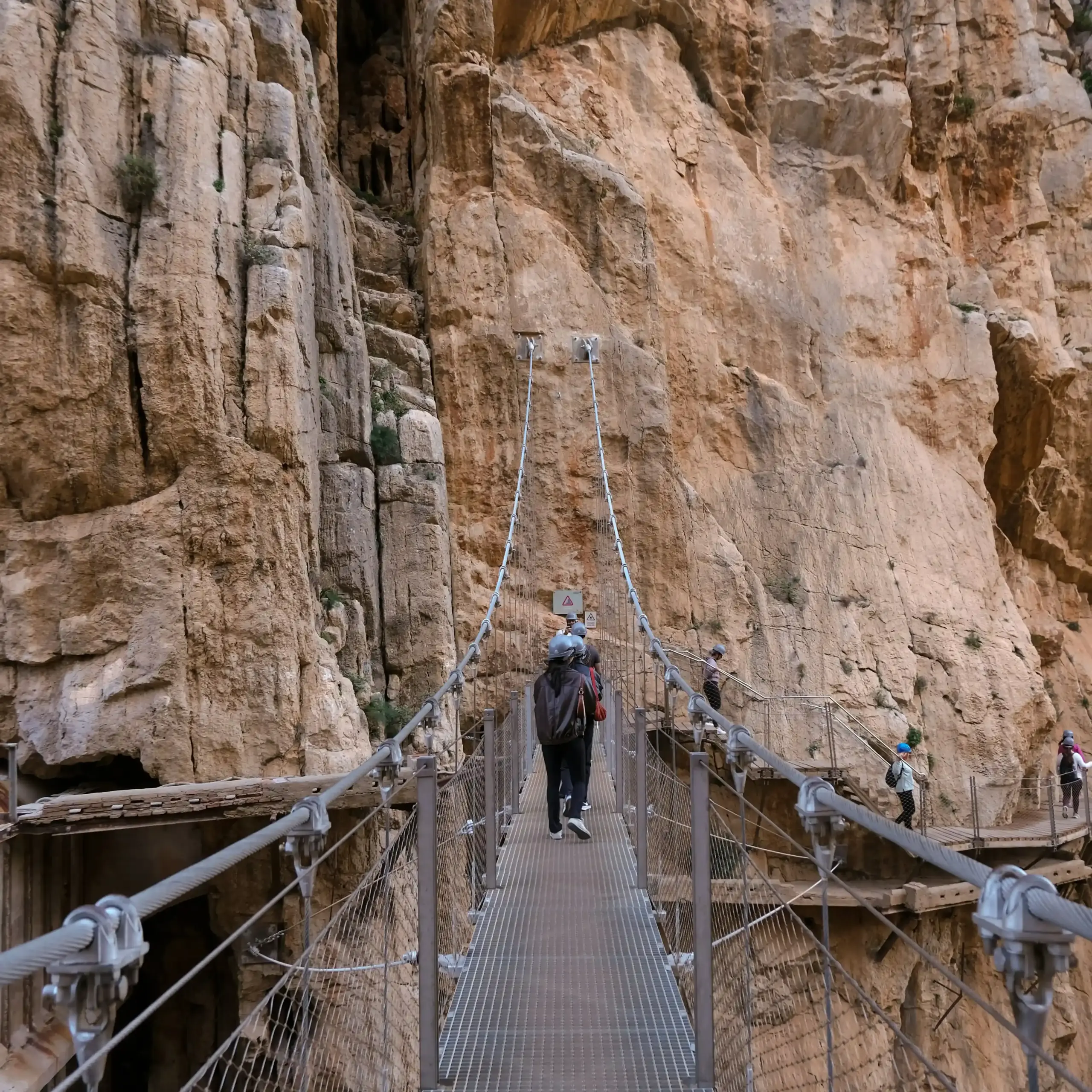 Visitatori attraversano una passerella sospesa tra le pareti rocciose del Desfiladero de los Gaitanes nel Caminito del Rey.