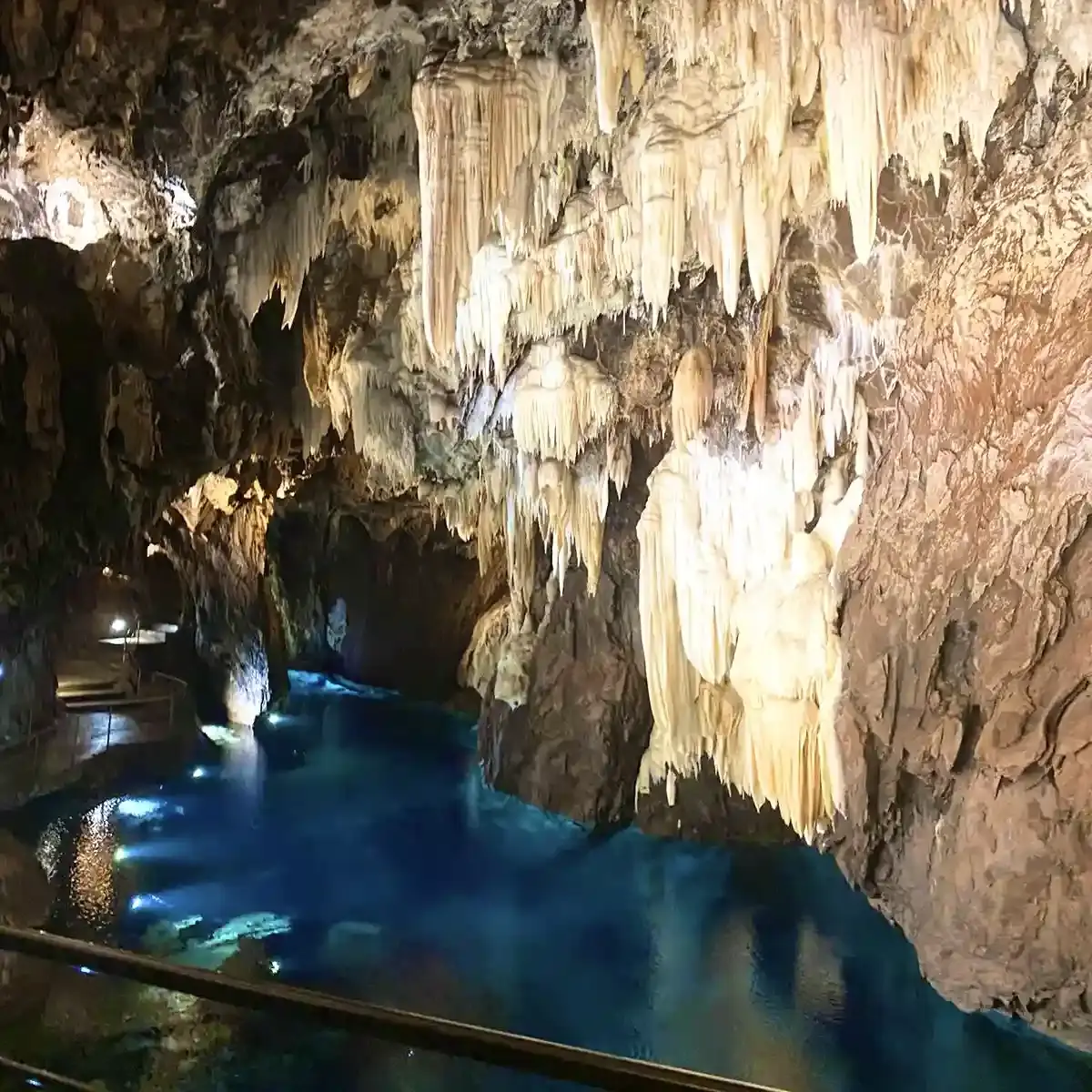 Interno della Cueva del Tesoro, la grotta marina vicino a Malaga, con formazioni rocciose illuminate e acqua sotterranea