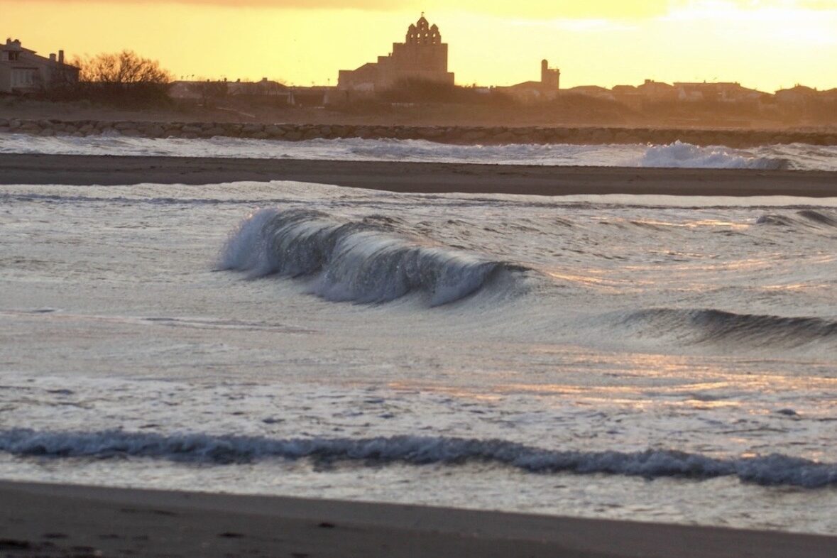 Onde del mare al tramonto sulla spiaggia di Saintes-Maries-de-la-Mer, con cielo rosa e atmosfera suggestiva in Camargue