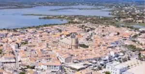 Vista di Saintes-Maries-de-la-Mer, con la chiesa fortificata, le case bianche affacciate sulla spiaggia della Camargue e allle spalle le paludi