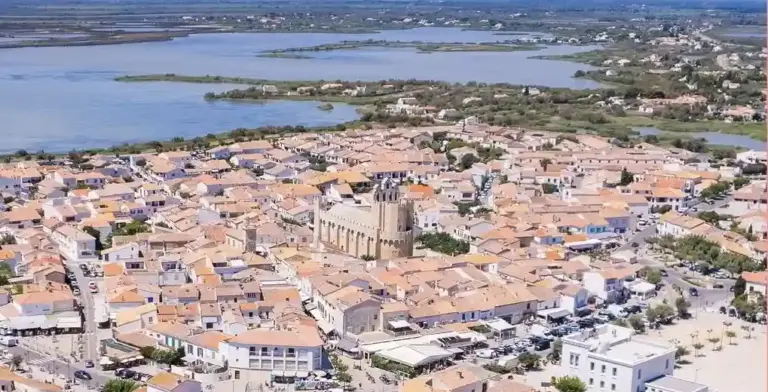 Vista di Saintes-Maries-de-la-Mer, con la chiesa fortificata, le case bianche affacciate sulla spiaggia della Camargue e allle spalle le paludi