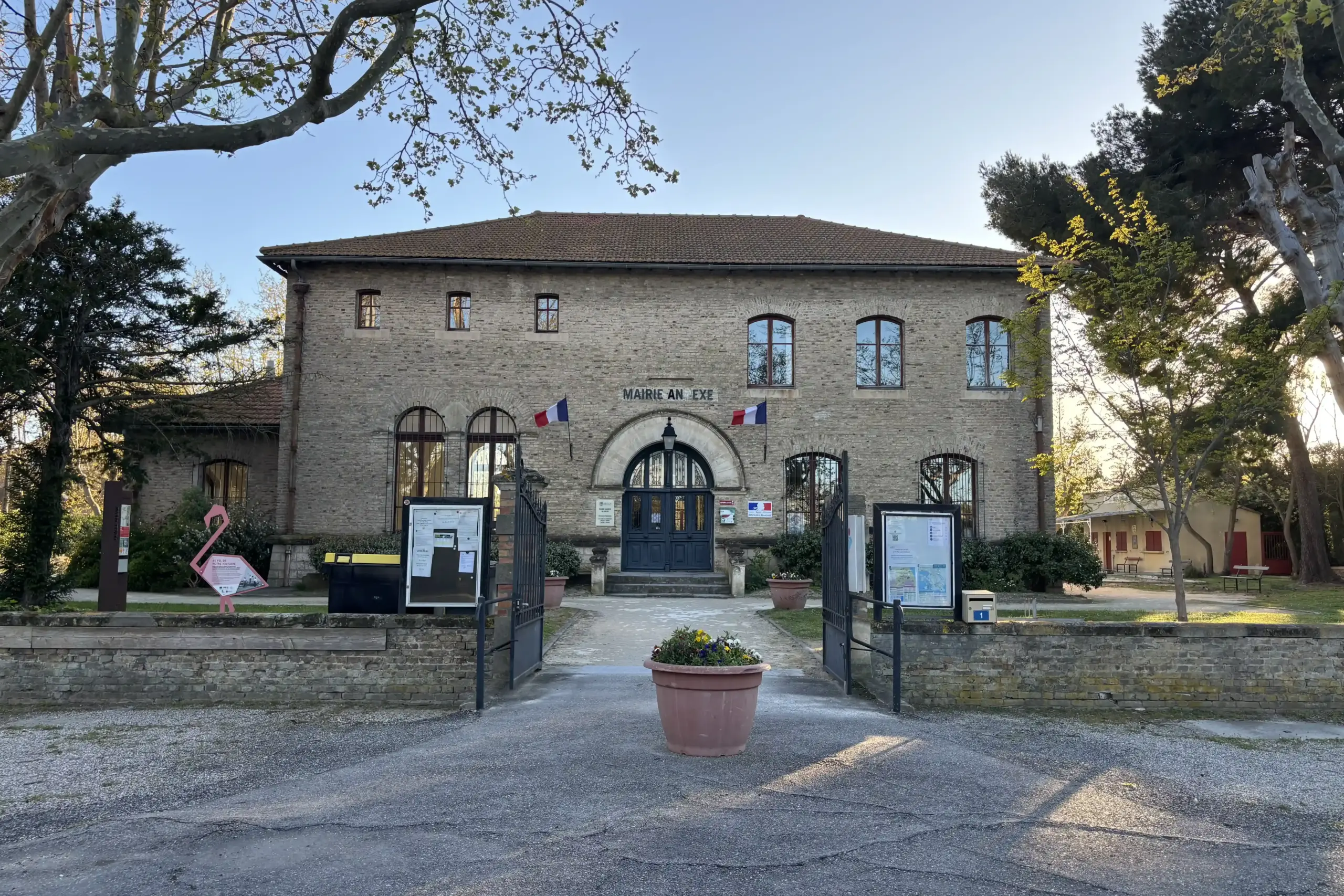 Facciata della Mairie Annexe di Salin-de-Giraud, edificio in pietra con bandiere francesi e alberi nel cuore della Camargue